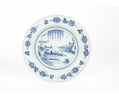 A blue and white English 18th Century tin glazed earthenware 'delftware' charger, with decoration of waterside buildings in t