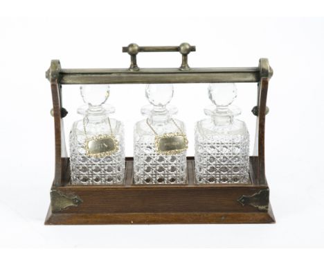 A wood and metal mounted decanter holder with three cut glass decanters, of tantalus type construction, two of the decanters 