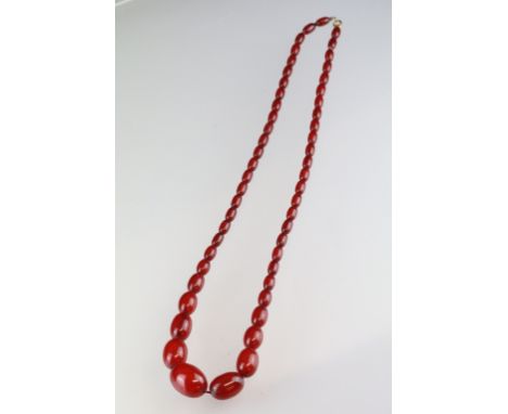Cherry bakelite beaded necklace having oval graduating beads with a spring ring clasp. Measures 28 inches. 