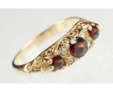 Garnet 9ct yellow gold boat head ring, three graduated round mixed cut rubies, the principal ruby diameter approx 5mm, four s