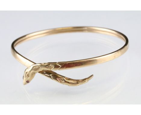 Ruby yellow metal snake bangle, two ruby eyes, engraved decoration to the head, width of bangle approx 3.5mm 