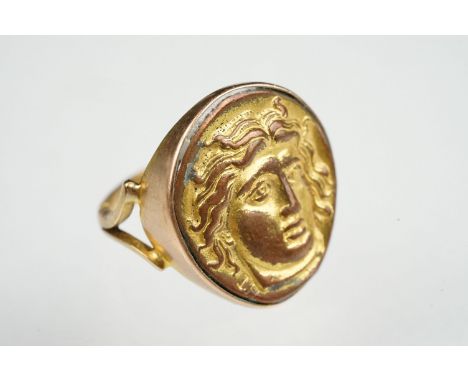 Cameo ring, the gilt metal cast panel depicting a head, rubover yellow metal settings and shank, V shaped shoulders, ring siz