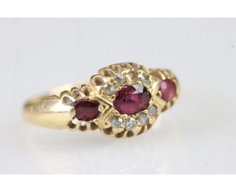 18ct gold ruby and diamond ring set with a central oval cut ruby flanked by two round cut rubies with diamond accent stones. 