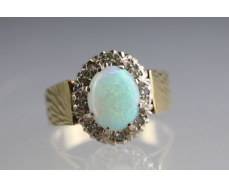 Opal and diamond 18ct yellow gold cluster ring, the oval cabochon precious white opal displaying violet, blue, gree, yellow, 