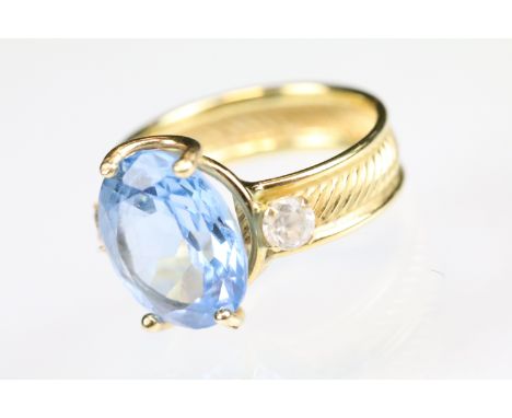 Blue and white stone ring, the central stone possibly a synthetic blue spinel, the band stamped 750, textured band, ring size