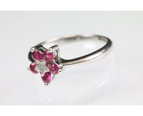 Ruby and diamond 9ct white gold flower head ring, central small round eight cut diamond to centre, illusion set, five small r