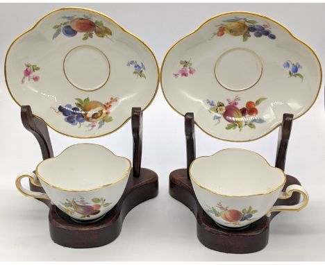 A pair of Meissen cups and saucers on wooden stands, marks to base, saucer W.14cm