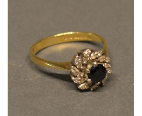 An 18ct. Gold, Sapphire And Diamond Cluster Ring, with a central sapphire surrounded by diamonds within a pierced setting 