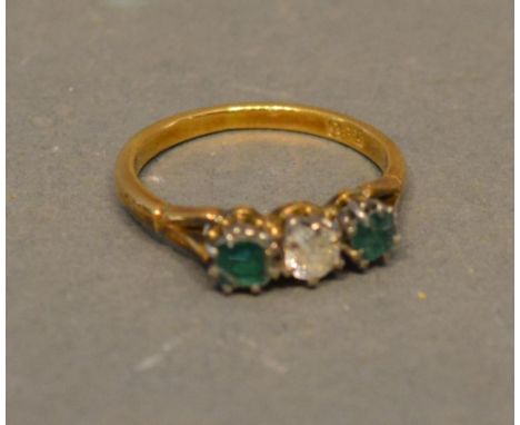 An 18ct. Gold Diamond And Emerald Three Stone Ring, set with a central diamond flanked by emeralds claw set 