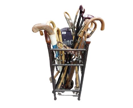 A collection of various Walking Sticks, Canes, Sporting Sticks and a Tennis Racket, all in an ornate stick and umbrella stand