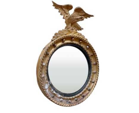 A Regency period gilt convex Wall Mirror,&nbsp;with carved eagle crest on a ball moulded frame, 31"h x 22"w (79cms x 56cms). 