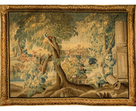 An 18th Century Flemish Verdure Tapestry,&nbsp;with View of Village through the Trees, with a Hound by a column and exotic Bi