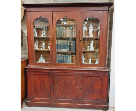 A Victorian stained pine Bookcase, the moulded pediment over three Middle Eastern style arched and glazed doors on a base wit