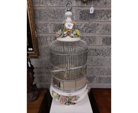 A flower encrusted ceramic and aluminium&nbsp;wire Bird Cage, enclosing a taxidermy stuffed model of a small bird. (1)