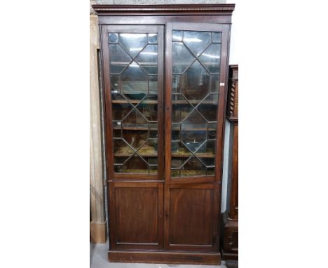 A good 19th Century mahogany slender one piece Bookcase, with dentil inlaid cornice over two astragal glazed doors enclosing 