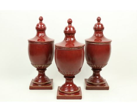 A set of 3 large burgundy ground ceramic Urns and Covers, each on square stem base. (3) 