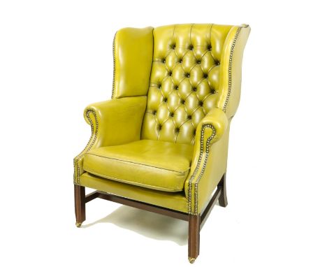 A Georgian style mahogany wing back Library Armchair, with button back and cushion seat covered in olive hide on front square