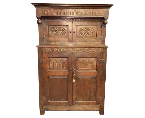An oak Court Cupboard, in the late 17th Century style, the hangover cornice with a series of arches above two single panel do