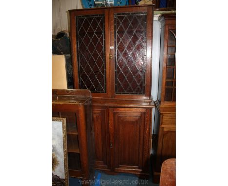 A late 19th c. Oak glazed Bookcase on Cupboard having plain top over a pair of opposing leaded frosted glazed 58 pane doors o