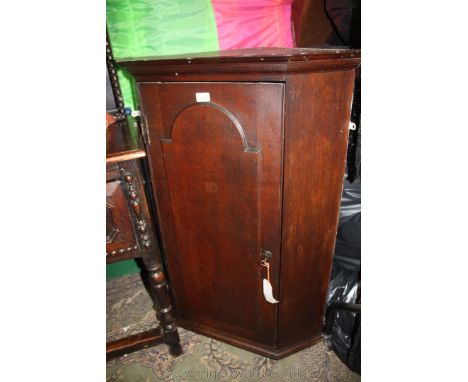 An early 19th c. Oak wall hanging Corner Cabinet, having moulded cornice over the single door with applied arch top moulded p