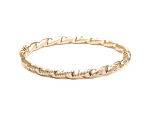 South Bucks Hospice Charity lot - A hinged bangle in 9ct yellow gold, of twisted design, fastens with tongue and groove clasp