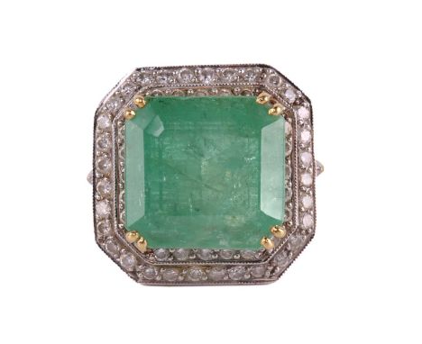 An emerald and diamond cluster ring, featuring a step-cut emerald with a translucent light green-coloured body, approximately