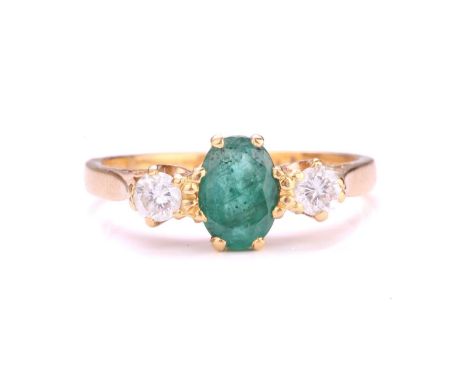 A three-stone emerald and diamond ring, centrally set with an oval-cut emerald with deep green body colour, approximately mea