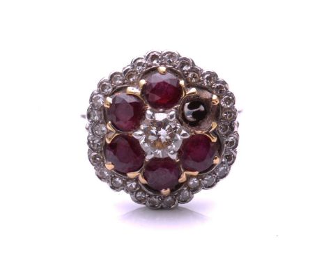 A ruby and diamond cluster ring; the principal round brilliant cut diamond in a raised claw mount above a border of six circu