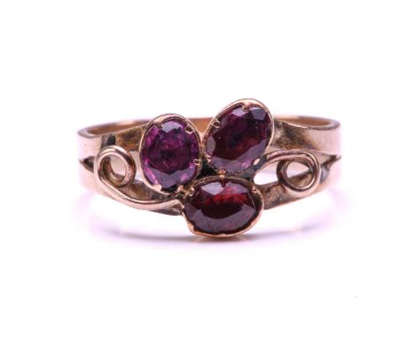 A Ruby and Garnet floral ring, formed from two Garnets claw set with a Ruby into a petal form on a yellow metal shank (tests 