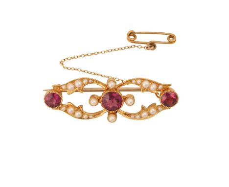 An Edwardian garnet and pearl brooch, containing three round-cut rhodolite garnets in collets, in scrollwork mount adorned wi