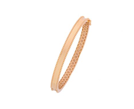 A hinged bangle set with diamonds, comprising a row of brilliant-cut diamonds pavé-set on yellow metal with a granulated edge