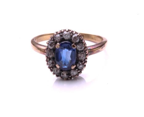 A sapphire and diamond cluster ring; the oval cut sapphire claw mounted within a border of mixed old cut diamonds, to a plain