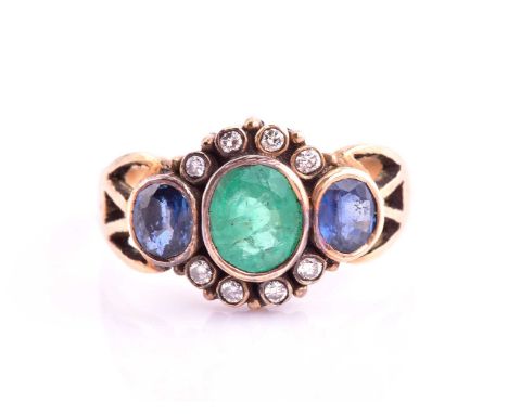 An Emerald and Sapphire dress ring, consisting of a central rub-over set oval emerald measuring 6x5.2mm flanked by two oval s