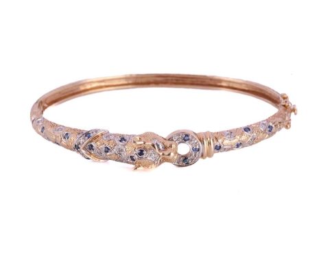 A two-toned panther bangle set with sapphires and diamonds, the hinged bangle features a panther head motif with an annular r