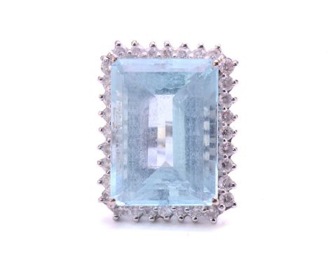 A large aquamarine and diamond cluster ring, featuring a rectangular step-cut aquamarine with pale blue body colour, approxim