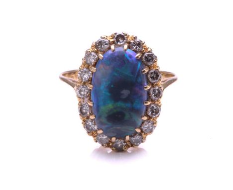 A black opal and diamond ring, the oval cabochon opal claw mounted within a border of round brilliant cut diamonds, to a plai