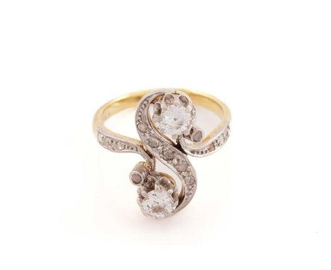 A diamond Toi et Moi ring, of a twisted 'S' form, set with two larger old-European cut diamonds representing the entwining of