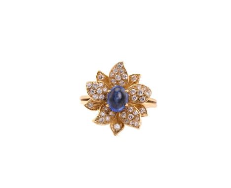 An 18ct gold sapphire and diamond flower ring, comprises an oval sapphire cabochon with a high dome, measuring 6.4 x 5.1 mm, 