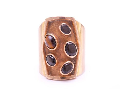 A Modernist style ring set with tiger's eye and black star sapphires, comprising an oval tiger's eye cabochon displaying chat