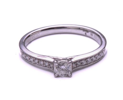 A single stone diamond cross over ring; the principal round brilliant cut diamond in cross over mount above diamond set shoul