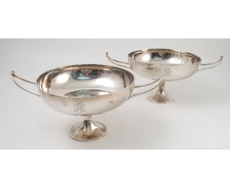 A pair of silver two handles trophy cups, the shallow circular bowl engraved with initials, having a pair of triangular handl