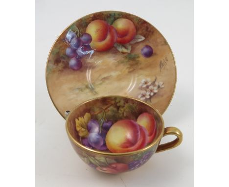 A Royal Worcester cabinet cup and saucer, the cup interior and exterior hand painted with fruit to a mossy background, dated 