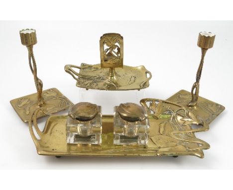 An Art Nouveau brass desk set, comprising inkstand with two inkwells, a pair of candlesticks and a match box holder, all deco