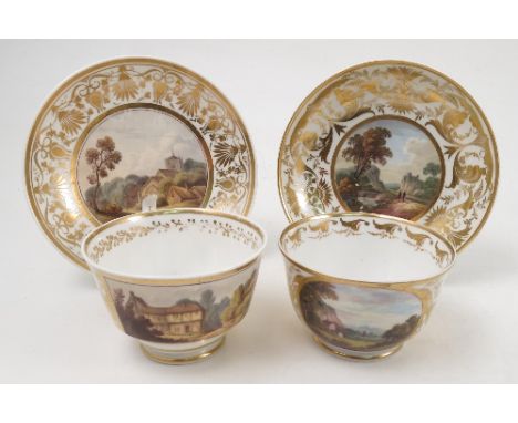 Two 19th century Derby porcelain tea cups, decorated with reserves of buildings in landscape to a white and gilt ground, one 