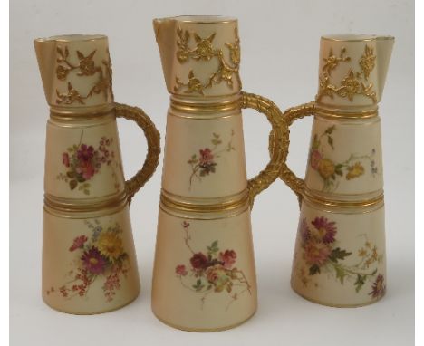 Three Royal Worcester blush ivory claret jugs, with moulded handles, decorated with flowers, dated 1904, 1906 and 1908, shape