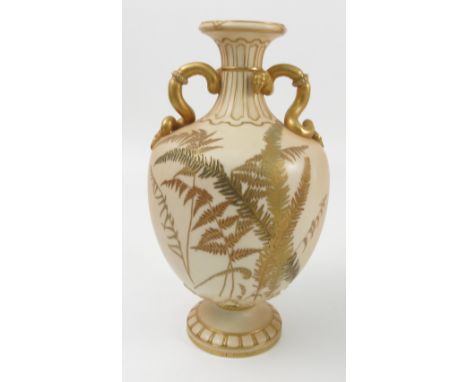 A 19th century Royal Worcester blush ivory vase, decorated with gilt ferns, having snake handles and raised on a pedestal foo