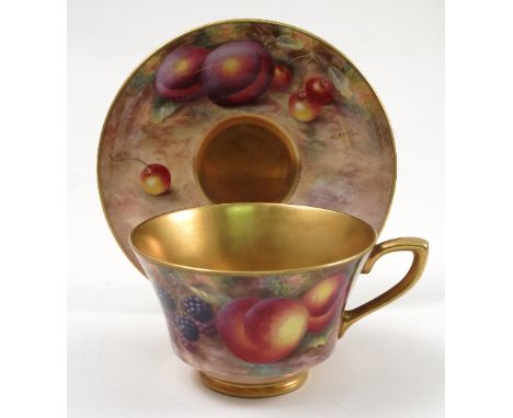 A Royal Worcester cabinet cup and saucer, hand painted to the exterior of the cup and the saucer with fruit to a mossy backgr