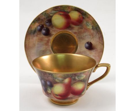 A Royal Worcester cabinet cup and saucer, hand painted to the exterior of the cup and the saucer with fruit to a mossy backgr
