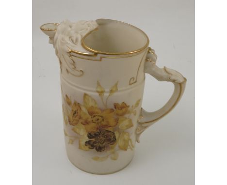 A Royal Worcester ivory jug, of cylindrical form, with lion mask spout and paw moulded handle, decorated with yellow flowers,