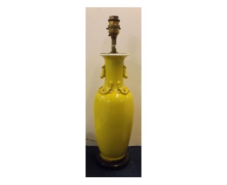 Oriental yellow glazed oil lamp with raised decoration and a turned wooden base, 17ins tall 